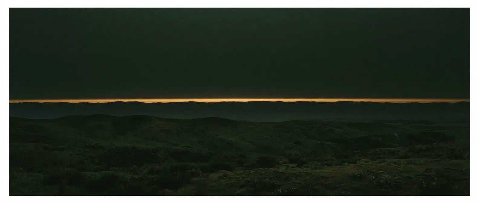 Low sun on the Canterbury plains, a single amber band along the horizon under a dark green sky.